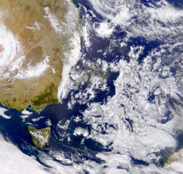 Satellietfoto van de Tasmanzee gedeeltelijk bedekt door wolken. Links is een deel van Australië met daaronder Tasmanië. NASA. Wetenschap